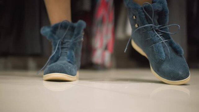 Close up of blue suede ankle boots with fur trim and laces on light colored floor. camera focuses on texture detail showing slight movement as feet shift position indoors. Soft lighting