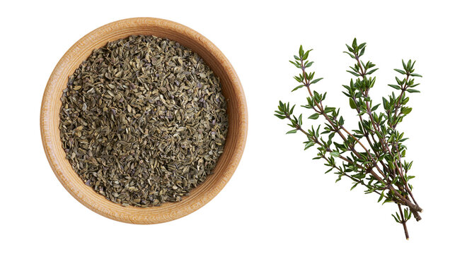 Isolated dried thyme spice in a wooden bowl with fresh green aromatic herb sprigs, cooking ingredient.