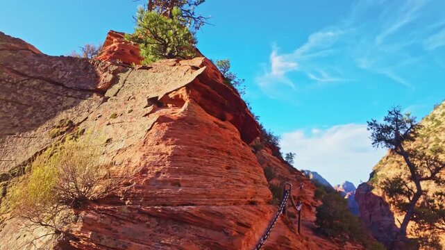 Golden sunrise light glows over the chained trail leading to Angels Landing in Zion National Park