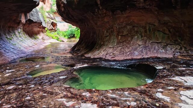 A scenic stream flows through water pools within the iconic Subway formation in Zion National Park