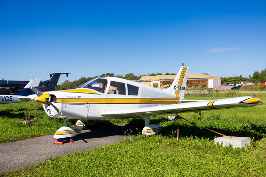 Neuville, Quebec, Canada, August 29, 2026 - Two seat yellow and white Piper Cherokee 140 displayed in airport fiels during public event