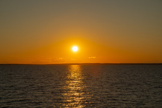 the water surface of a river or lake with sun glare at sunset