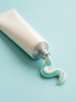 Toothpaste tube squeezing out blue and white gel