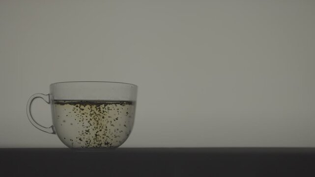 Slow Motion Tea Leaves Infusing in Hot Water in Transparent Cup_Settled