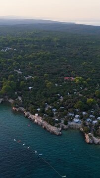 FKK Naturist Baldarin Campsite In Punta Kriza On Cres Island, Croatia, Filmed By Drone During A Beautiful Summer Evening. Aerial Views Show Campervans, Motorhomes, Coastal Nature at Sunset