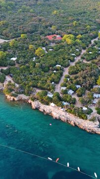 FKK Naturist Baldarin Campsite In Punta Kriza On Cres Island, Croatia, Filmed By Drone During A Beautiful Summer Evening. Aerial Views Show Campervans, Motorhomes, Coastal Nature at Sunset