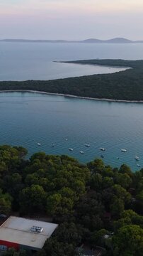 FKK Naturist Baldarin Campsite In Punta Kriza On Cres Island, Croatia, Filmed By Drone During A Beautiful Summer Evening. Aerial Views Show Campervans, Motorhomes, Coastal Nature at Sunset