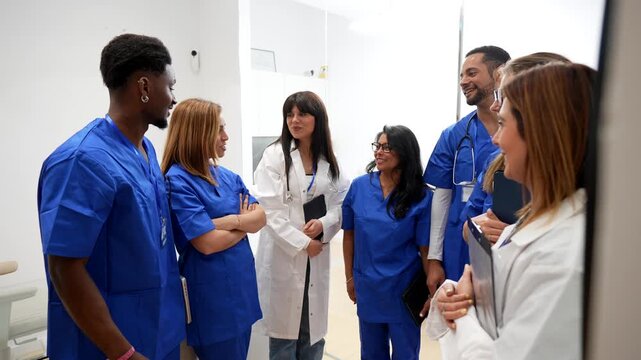 Motivated multicultural group of doctors and nurses celebrating a success with a high five and applause in a hospital hallway. Teamwork, cooperation, and achievement in the medical field