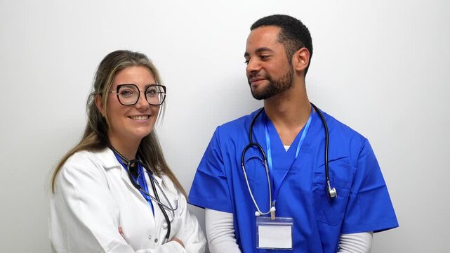Confident female doctor and a male nurse smiling and looking at the camera, standing together as a professional healthcare team isolated on a white background in a medical clinic