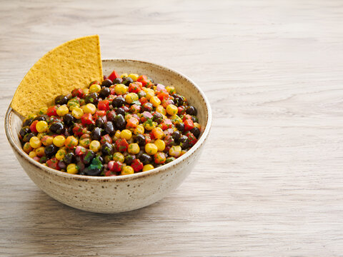 Black bean and corn salsa with a tortilla chip in a ceramic bowl