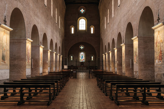Interior view of the nave with wooden pews and brick arches in the Church of Saints Vincent and Anastasius at Tre Fontane Abbey in Rome Italy