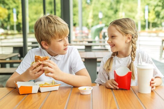 Children eating burgers and fries together at fast food restaurant