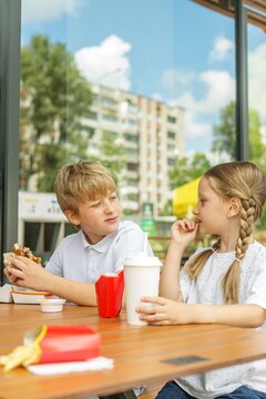 Two Children Chatting Over Burgers and Fries at Fast Food Restaurant