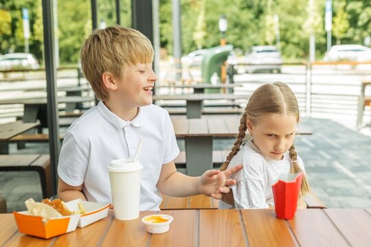 Annoyed younger sister reacting to older brother during fast food meal