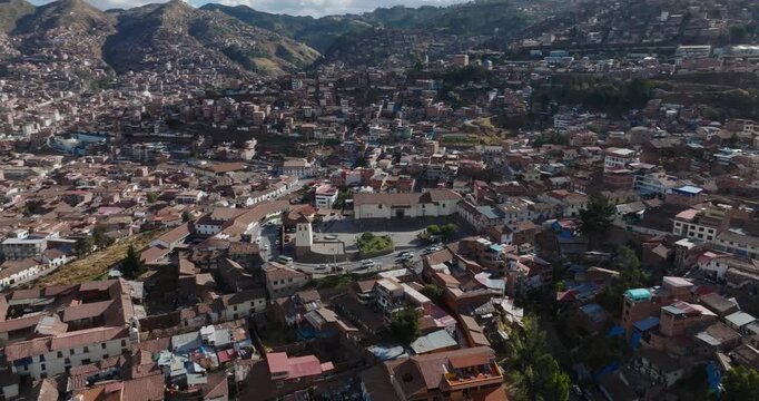 Aerial view of the historic city center of Cusco with its dense urban fabric, terracotta rooftops, and colonial architecture in Peru