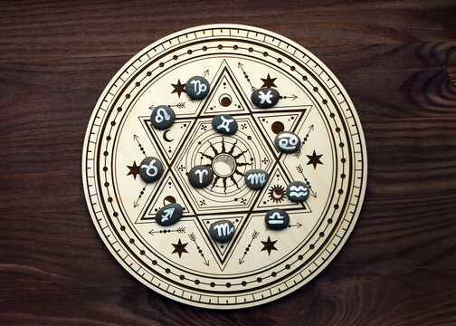 Stones with the emblems of the zodiac signs are laid out on a wooden altar for divination. Fortune-telling, witchcraft, and esoteric spiritual practices.