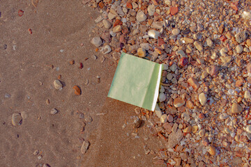 Green Paper Note Mockup Lying on Sandy Beach and Pebble Shoreline © Dawud