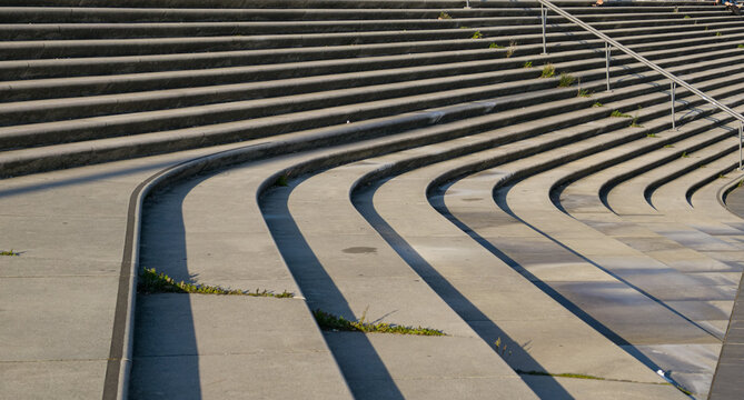 Concrete steps create a repetitive curved pattern in sunlight with shadows