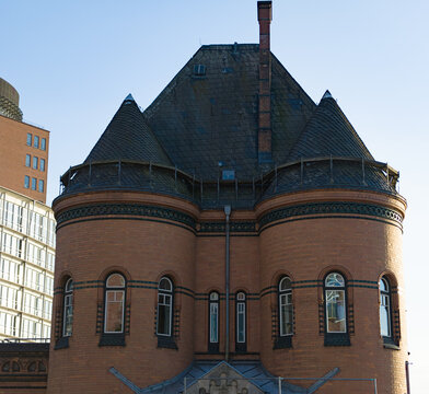 Historic brick building facade featuring two rounded turrets and a dark slate roof