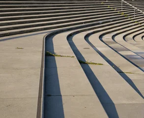 Modern concrete amphitheater steps creating abstract patterns with sunlight and deep shadows © 4kclips