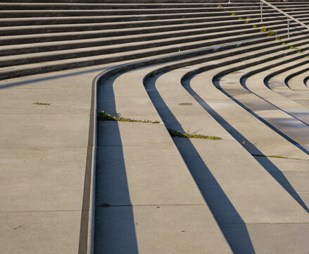 Modern concrete amphitheater steps creating abstract patterns with sunlight and deep shadows