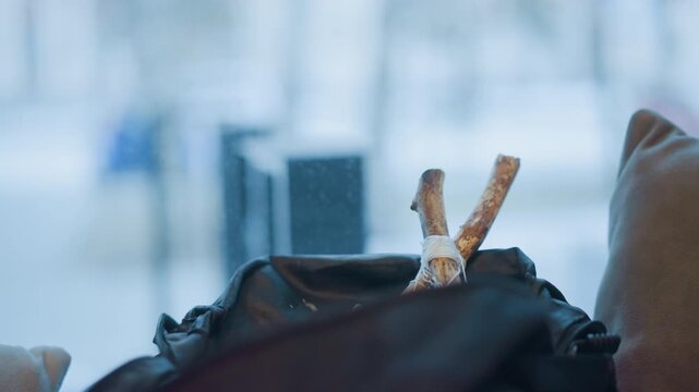 Close up of tied stick emerging from open black bag with soft lighting and blurred background. scene shows texture detail of wood string binding fabric material on clothing indoor
