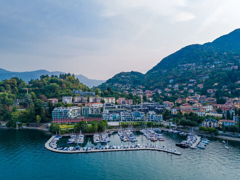 Aerial drone view of Porto Laveno marina in Laveno-Mombello town on the shores of Lake Maggiore in Italy, with picturesque lakeside scenery and Alpine mountains