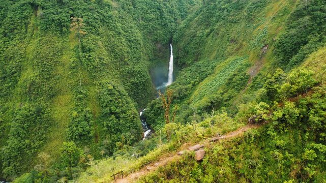 Aerial view of tall waterfall surrounded by lush green mountains in Costa Rica