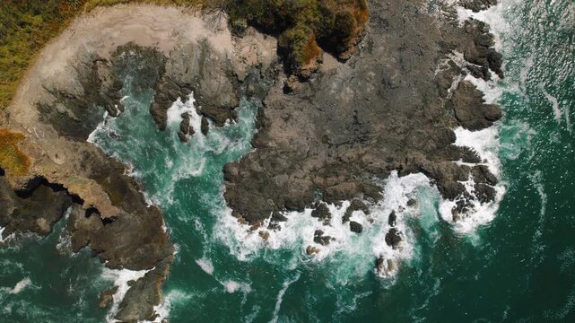 Aerial top view of black rocky coastline and turquoise ocean waves in Costa Rica