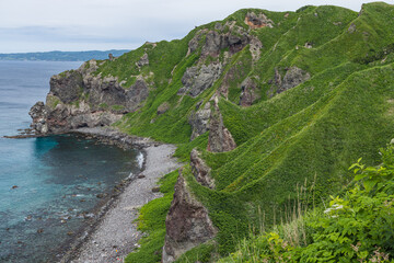 日本　北海道積丹町・神威岬のダイナミックな断崖絶壁と緑に覆われた険しい山肌 © pespiero