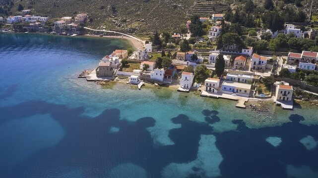 Drone shot, coastal town with white buildings on a deep blue sea and clear coastline, Bay of Emporio, Emporio, Symi, Dodecanese, Greek Islands, Greece