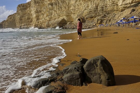 Red Beach, dream beach only accessible on foot in the neighboring bay of Matala, person on a quiet beach with rocks and blue sky, surrounded by rugged cliffs, Matala, south coast, Crete, Greek Islands, Greece