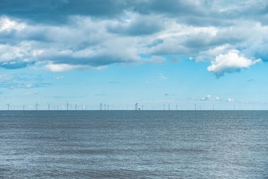 View looking out across the sea at an offshore wind farm on the horizon seen from Skegness beach in Lincolnshire, UK