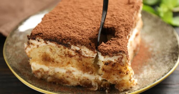 Eating delicious tiramisu at wooden table, closeup