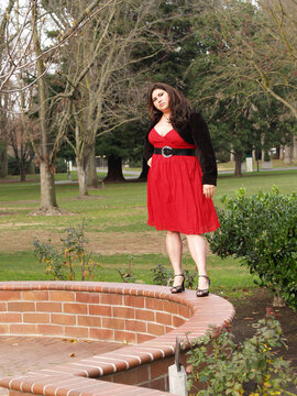 Young Hispanic Woman Standing Outdoors In Red Dress