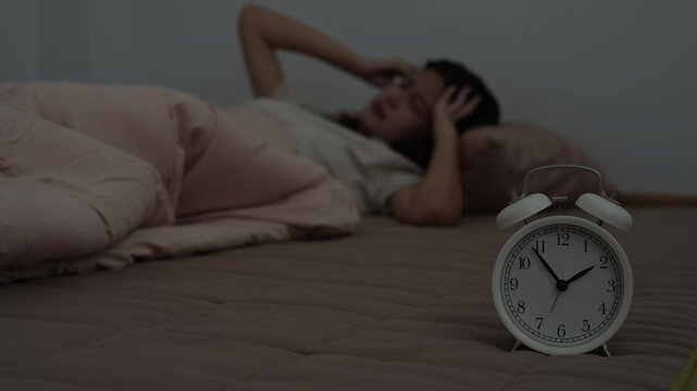 asian woman in bed late trying to sleep suffering insomnia, sleepless or scared in a nightmare, looking sad worried and stressed. Tired and headache or migraine waking up in the middle of the night.