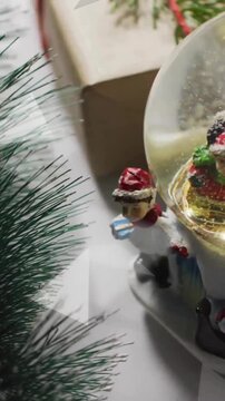 Animation of snow falling over christmas snow globe and decorations