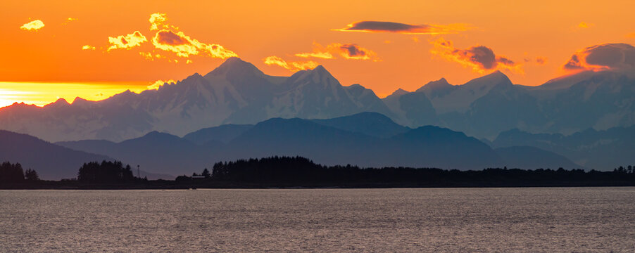 Dramatic sunset over the mountain peaks, glaciers, forests and coastline of the  Glacier Bay National Park and Preserve,  Alaska, USA
