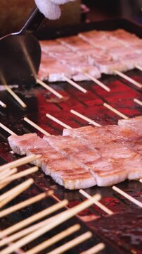 Wagyu beef skewers grilling on hot teppanyaki teppan iron plate, premium Japanese marbled meat on wooden sticks, traditional street food festival, Tokyo, Japan, market with local vendor stalls cooking