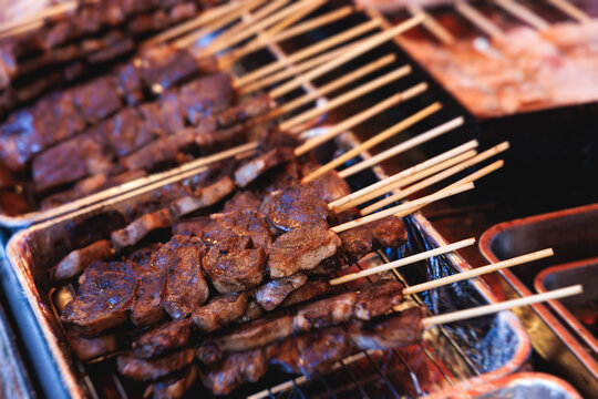 Wagyu beef skewers grilling on hot teppanyaki teppan iron plate, premium Japanese marbled meat on wooden sticks, traditional street food festival, Tokyo, Japan, market with local vendor stalls cooking