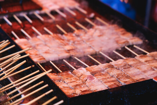 Wagyu beef skewers grilling on hot teppanyaki teppan iron plate, premium Japanese marbled meat on wooden sticks, traditional street food festival, Tokyo, Japan, market with local vendor stalls cooking