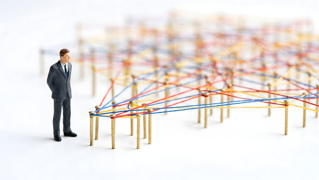 Miniature Businessman Standing Before Complex Network of Colorful Connections and Ties