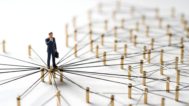 Miniature businessman standing on a connected network of pins representing corporate leadership