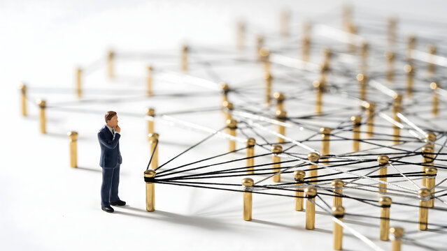 Miniature businessman analyzing a complex network and communication infrastructure