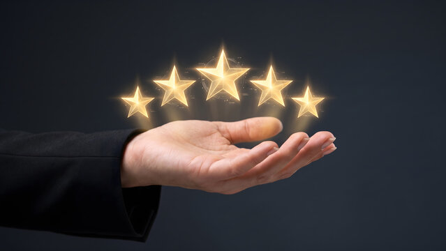 Hand holding five glowing golden stars for customer rating and feedback concept