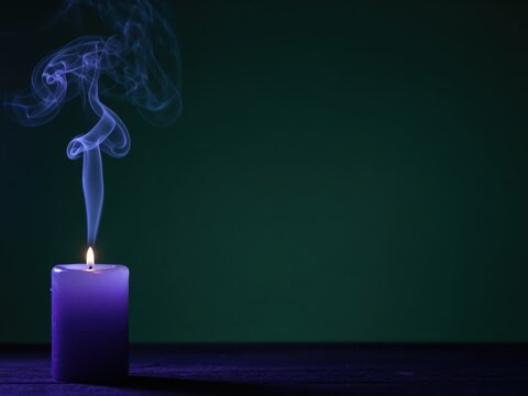 Purple candle with curling smoke against a dark background