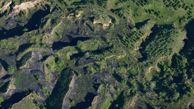 Dramatic aerial push-in revealing epic rugged basalt gully slopes of a dormant volcano in Ulan Hada, Inner Mongolia. Deep shadows and green vegetation contrast on the textured volcanic rock.