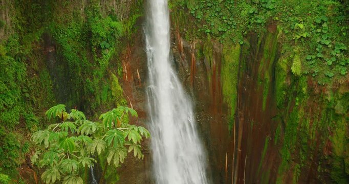 Tall waterfall Catarata del Toro against mossy rock cliff and green foliage in Costa Rica
