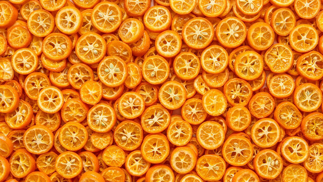 Close up of dried kumquat slices, scattered full frame texture in vibrant citrus orange