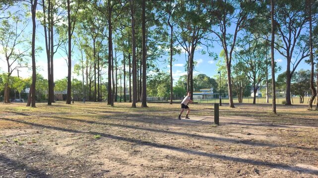 Caucasian man throwing a disc playing disc golf in a public park on a sunny day in Logan, Brisbane, Queensland, Australia.